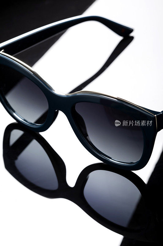 Fashionable sun glasses on reflective background with play of light and shadow.
